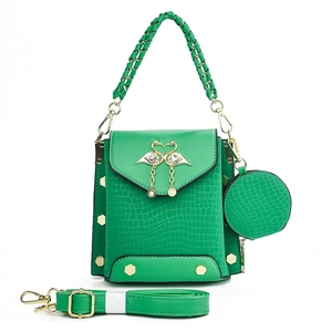 Detail of green crocodile-embossed handbag with braided handle and gold swan hardware
