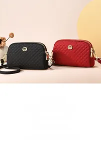 Détail de sacs bandoulière matelassés en nylon noir et rouge avec logos dorés