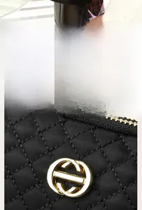 Détail du logo doré poli sur la surface matelassée noire du sac à bandoulière