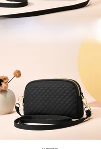 Gros plan du sac bandoulière matelassé noir avec double fermeture éclair et détails dorés
