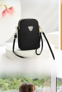 Detail of compact black nylon shoulder bag with triple zip compartments and gold hardware