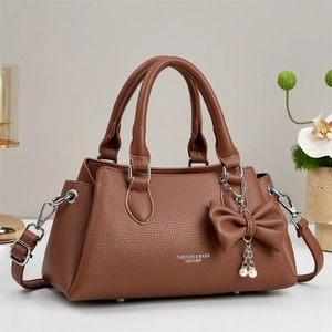 Brown lychee pattern tote bag with gold logo and pearl bow charm on white table