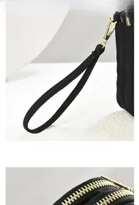 Detail view of black nylon bag showing durable gold zippers and portable wristlet strap