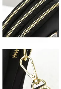 Detail of premium golden zippers and metal hooks on a black nylon crossbody shoulder bag