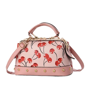 Pink Boston handbag featuring red cherry prints, gold rivets, and adjustable strap