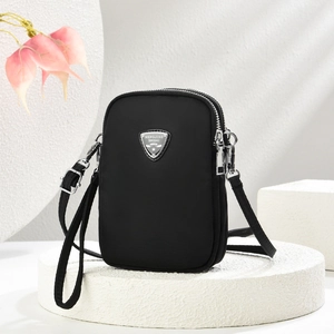Minimalist black three-layer nylon crossbody phone bag with metal logo on white geometric blocks