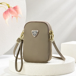 Khaki multi-layer nylon crossbody bag with gold zippers on a white marble pedestal