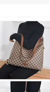 Detail view of large checkered tote bag with geometric logo pattern and leather straps