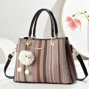 Brown woven tote bag with dark handles and a playful white plush monster charm