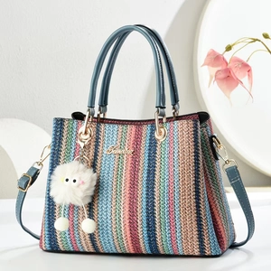 Rainbow striped woven tote bag with blue handles and a white monster charm accessory