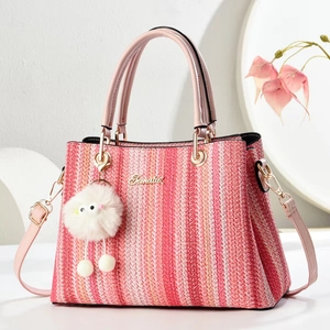 Detailed shot of pink striped woven tote with gold Fematoz logo and plush monster charm