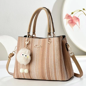Detailed side view of woven tote bag with leather strap and plush monster charm