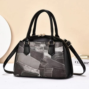 Close-up of color-block leather tote bag with contrast stitching and gold metal hardware