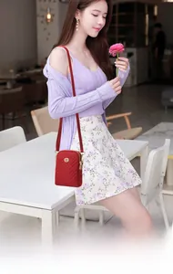 Quilted red crossbody phone bag with gold logo shown worn in a lifestyle setting