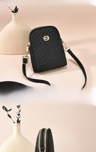Close-up of black quilted nylon phone bag featuring golden double zippers and logo