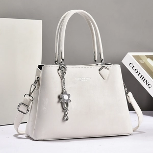 Minimalist white leather tote bag with silver flower charm and adjustable shoulder strap