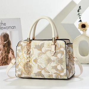 Sac à bandoulière blanc élégant avec broderies florales et breloque perle, décor minimaliste