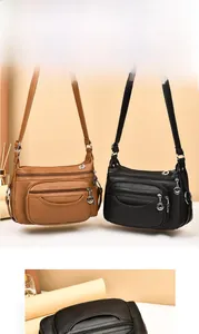 Detail of multi-pocket faux leather crossbody bag with metal zippers and wide strap