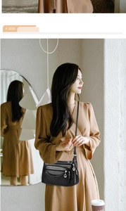 Detail of black multi-zipper PU leather crossbody bag worn by a model in casual setting