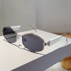 Détail de lunettes de soleil hexagonales en métal style Y2K sur présentoir blanc