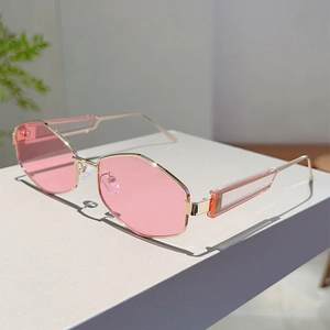 Détail de lunettes de soleil hexagonales roses avec monture dorée et branches