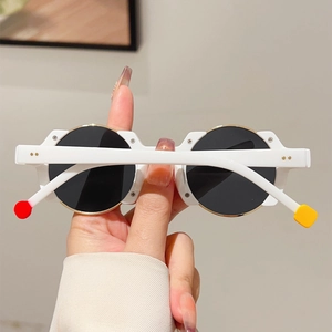 Detail of round sunglasses featuring white frames and colorful temple tips with rivets