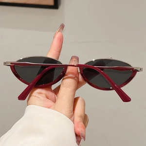 Close-up of retro narrow cat-eye sunglasses with dark red frame and black lenses