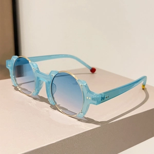 Detail view of round blue gradient lenses with gold metal trim and rice nail accents