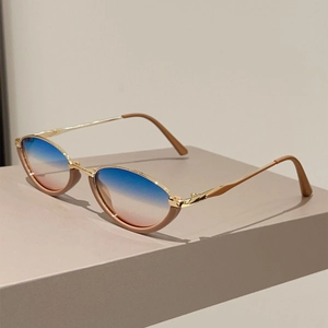 Close-up of vintage cat-eye sunglasses with gold metal temples and blue pink gradient lenses
