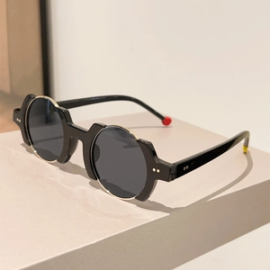 Detail of round black sunglasses featuring gold metal rims and signature colorful temple tips