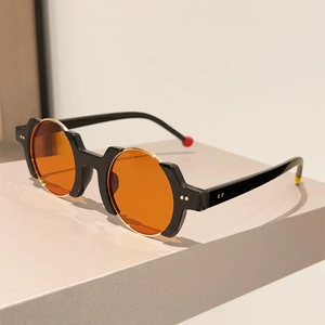 Detail view of round orange lenses with thick black frames and metal rivet accents