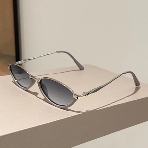 Detail view of oval cat-eye sunglasses with gray-purple frame and silver metal temples