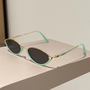 Detail view of cat-eye sunglasses with mint green frame and sleek gold metal temples