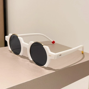 Detailed close-up of retro round white frame sunglasses with gold trim and rivets