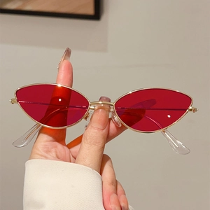 Vue détaillée de lunettes de soleil œil-de-chat dorées avec verres rouges translucides