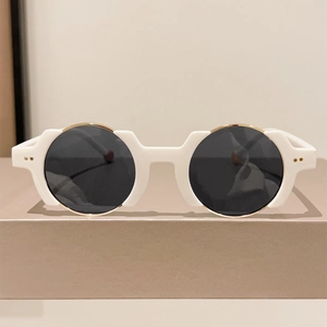 Close-up of retro white round sunglasses with gold metal trim and rivets on a display stand