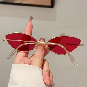 Détails des verres rouges et montures dorées de lunettes de soleil œil-de-chat