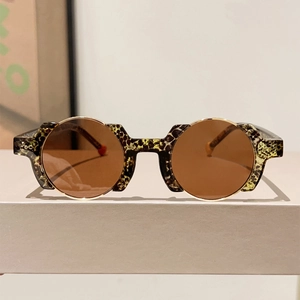 Detail of retro round sunglasses with leopard print frame and gold metal accents