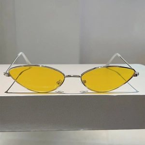 Vue frontale des lunettes œil-de-chat en métal argenté avec verres jaunes sur bloc