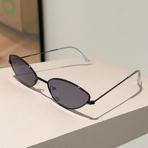 Détail d'une monture de lunettes de soleil fine en métal noir sur un support géométrique