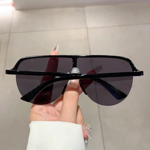 Détail de lunettes de soleil Y2K enveloppantes noires avec verres foncés et fini brillant