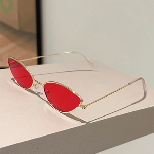 Détail de verres rouges œil-de-chat et monture en métal doré de lunettes tendance