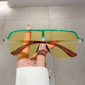Détail de lunettes Y2K avec monture vert translucide et verre dégradé jaune vif