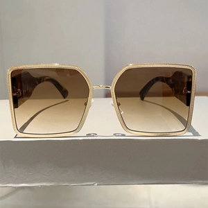 Detail of square gold metal sunglasses frame with brown gradient lenses and shell temples