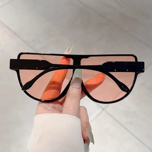 Close-up of pilot sunglasses with light orange lenses and black frame held by hand