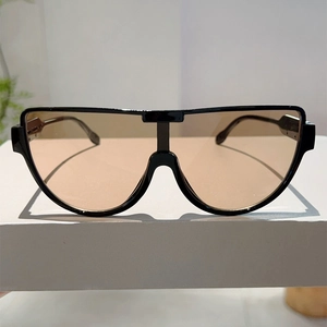 Detail of oversized pilot sunglasses featuring black frames and brown protective lenses