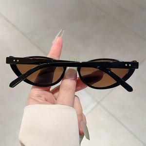 Detail of trendy black cat-eye sunglasses with brown lenses and silver dot accents
