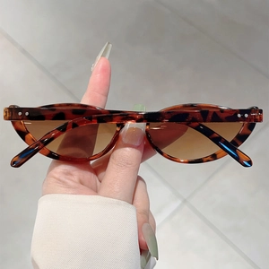 Detail of tortoise shell cat eye sunglasses featuring metal rivets and gradient brown lenses