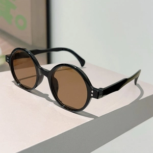 Detail view of vintage round black sunglasses with silver rivets and brown lenses