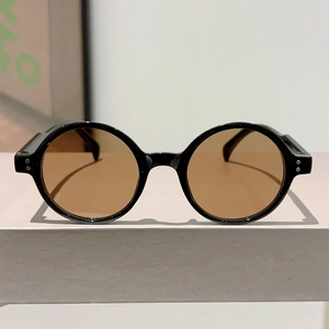 Close-up of retro round black sunglasses frame featuring silver rivets and amber lenses